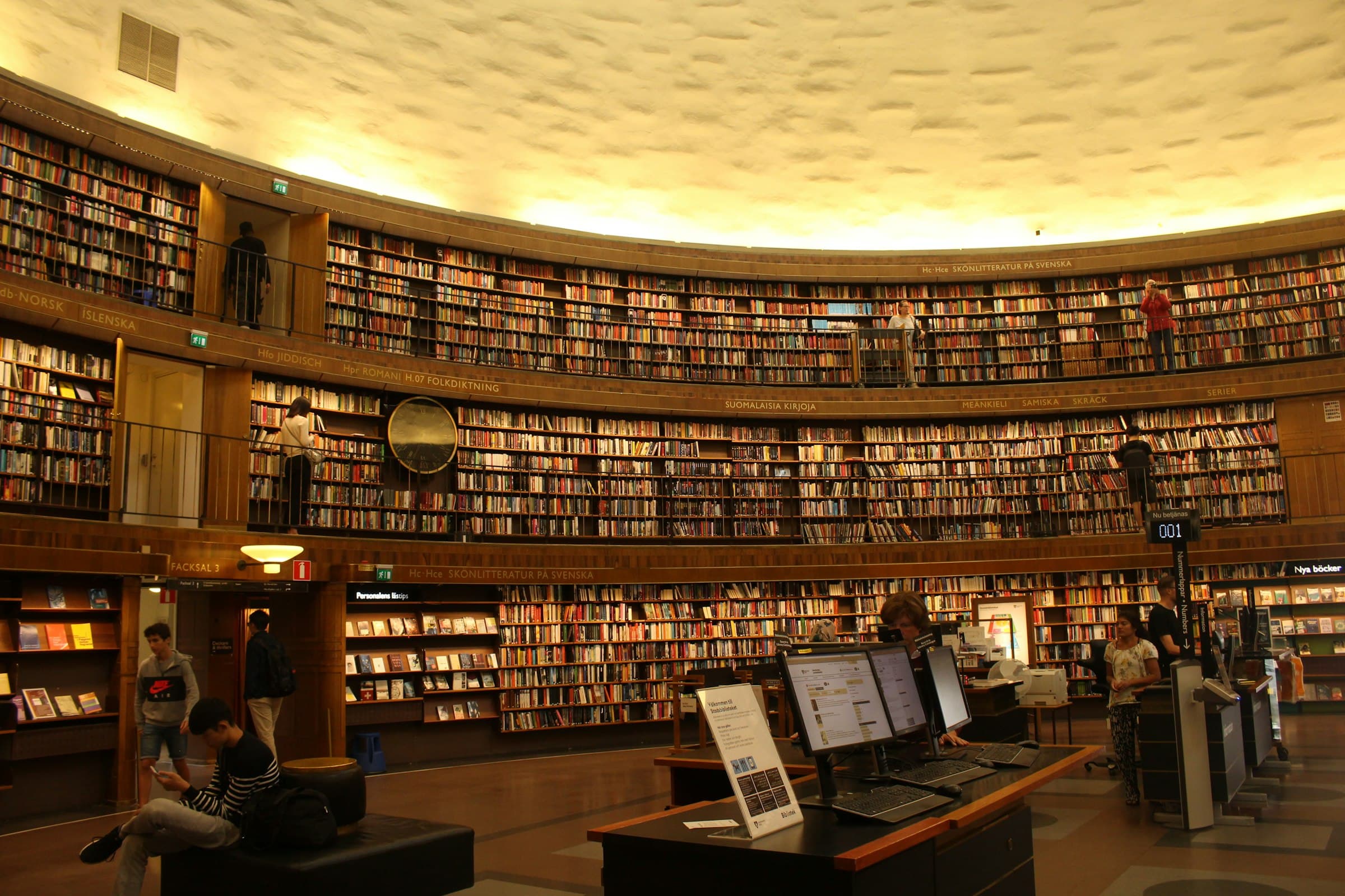The rotunda of the Stockholm Public Library, lined floor to ceiling with curved bookshelves under a glowing ceiling